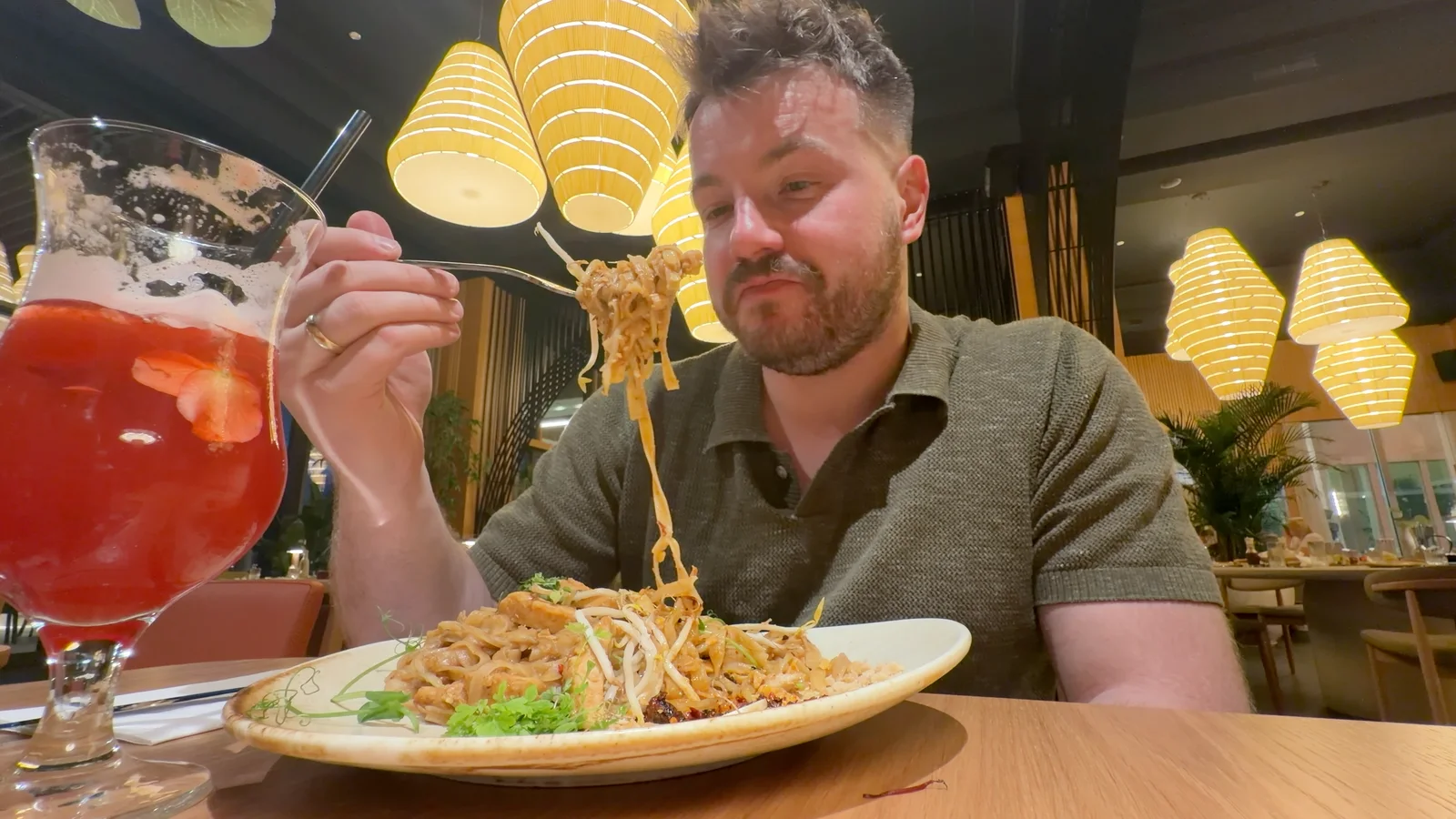 Kolacja w restauracji Monsoon w Hotelu Gołębiewski w Pobierowie, z pad thai i czerwonym napojem na stole.