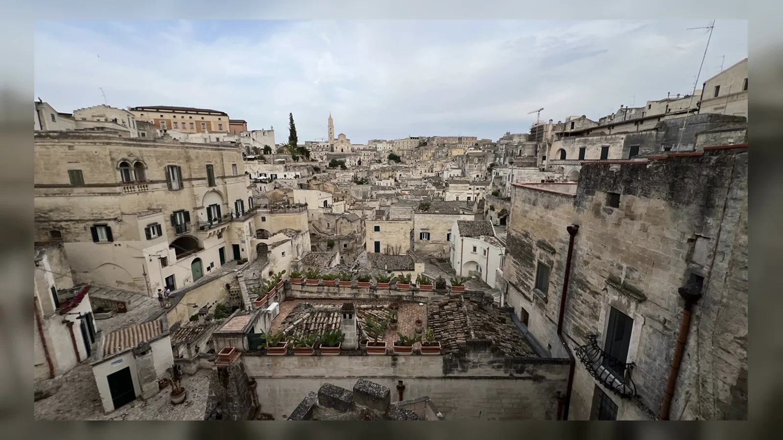 Panorama Sassi di Matera z kamiennymi domami i katedrą w tle.